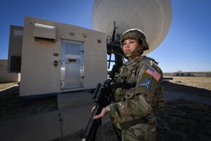 Στέλεχος της Space Force μπροστά από μεγάλη κεραία δορυφορικών επικοινωνιών
