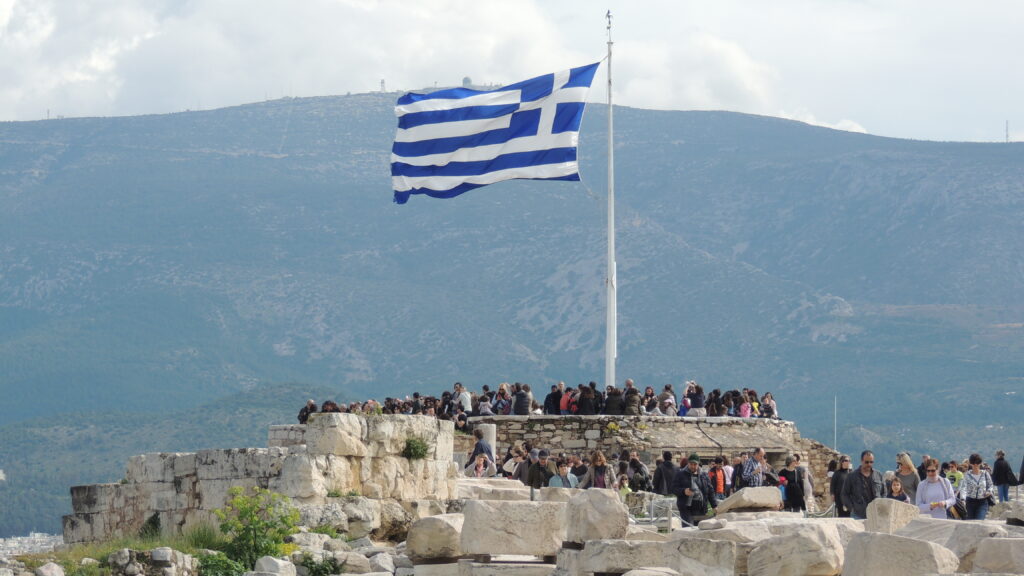 Η ελληνική σημαία στον ιστό της Ακρόπολης πάνω από τους επισκέπτες του Ιερού Βράχου