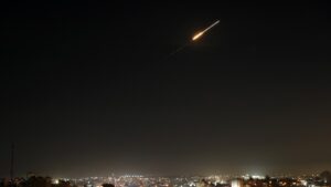 Φωτεινό ίχνος πυραύλου στον νυχτερινό ουρανό πάνω από κατοικημένη περιοχή